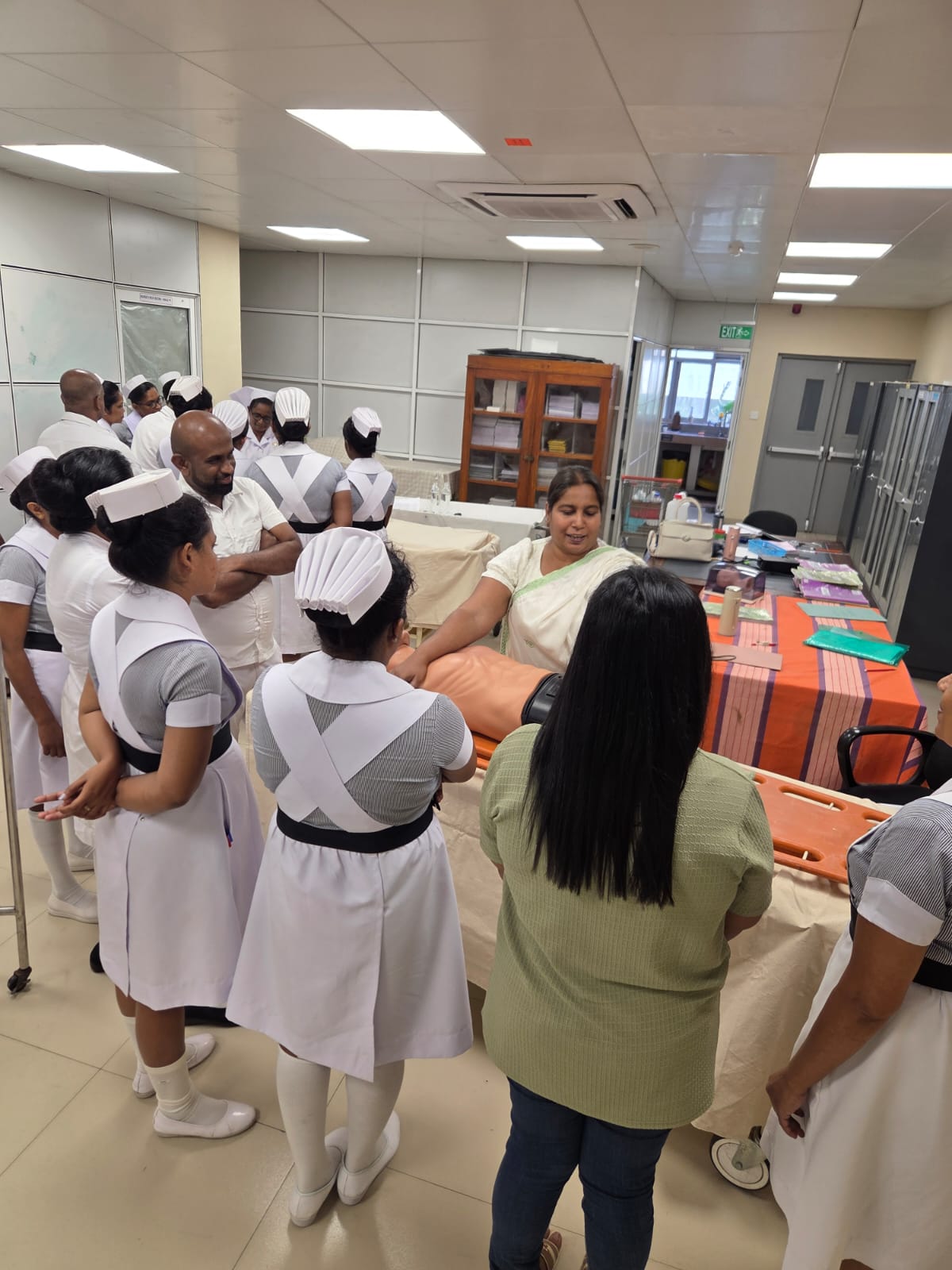 Hands-on ABCDE training demonstration with nurses gathered around a mannequin
